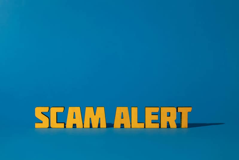 Partial image of bold yellow text reading 'SCAM ALERT' on a blue background.